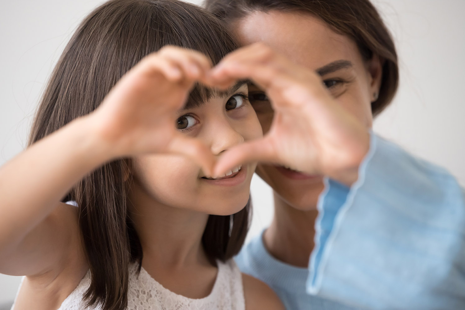 Child with mother making a heart with their hands